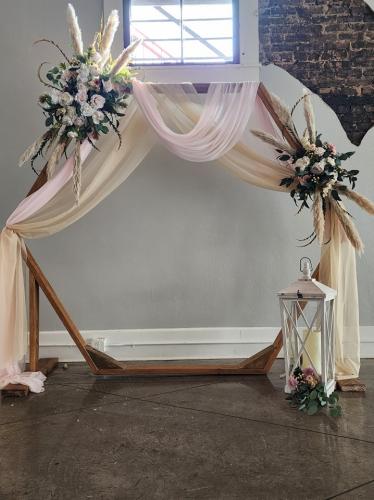 hexagon wedding arch with pastel flowers and drapery