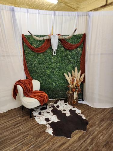 greenery wall photo backdrop with cow skull, cowhide rug, and pampas grass