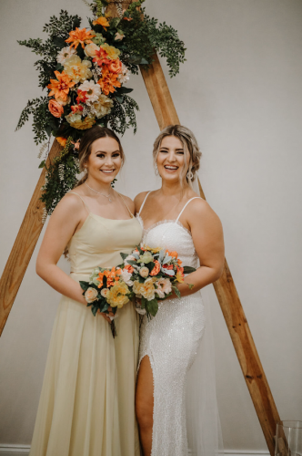 bride and bridesmaids under triangle wedding arch