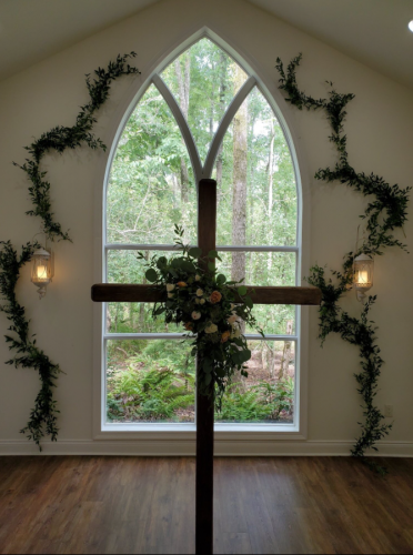 simple wooden cross with flower arrangement as altar piece